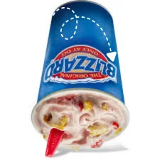 Dipped Strawberry Cheesecake Blizzard Treat held upside down, showing creamy vanilla soft serve blended with strawberry pieces and cheesecake chunks"